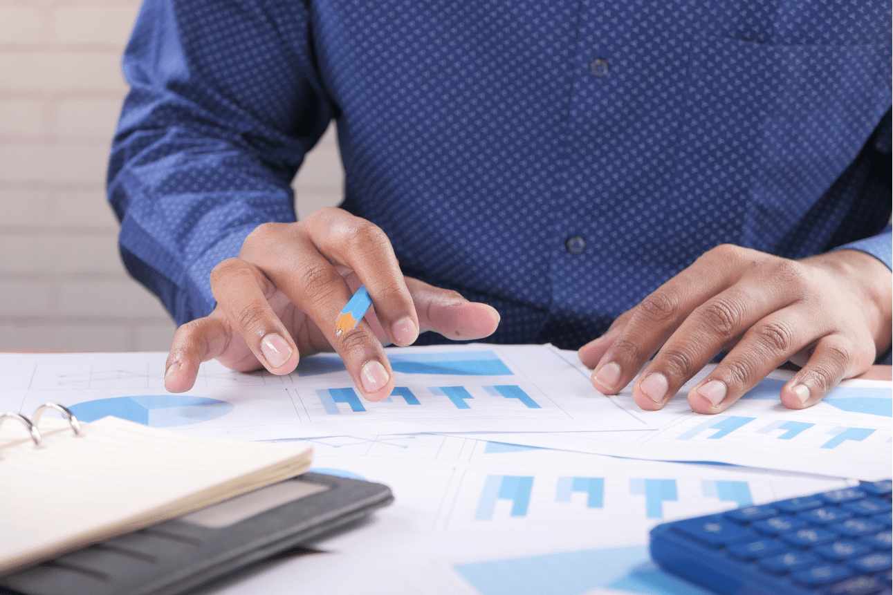 Man's hand with pen analyzing bar chart related to accounts payable outsourcing services