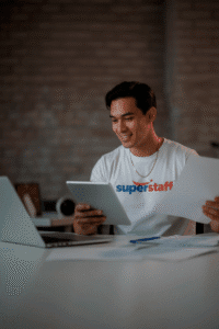 An outsourced accounting services professional with reading glasses is holding white papers.